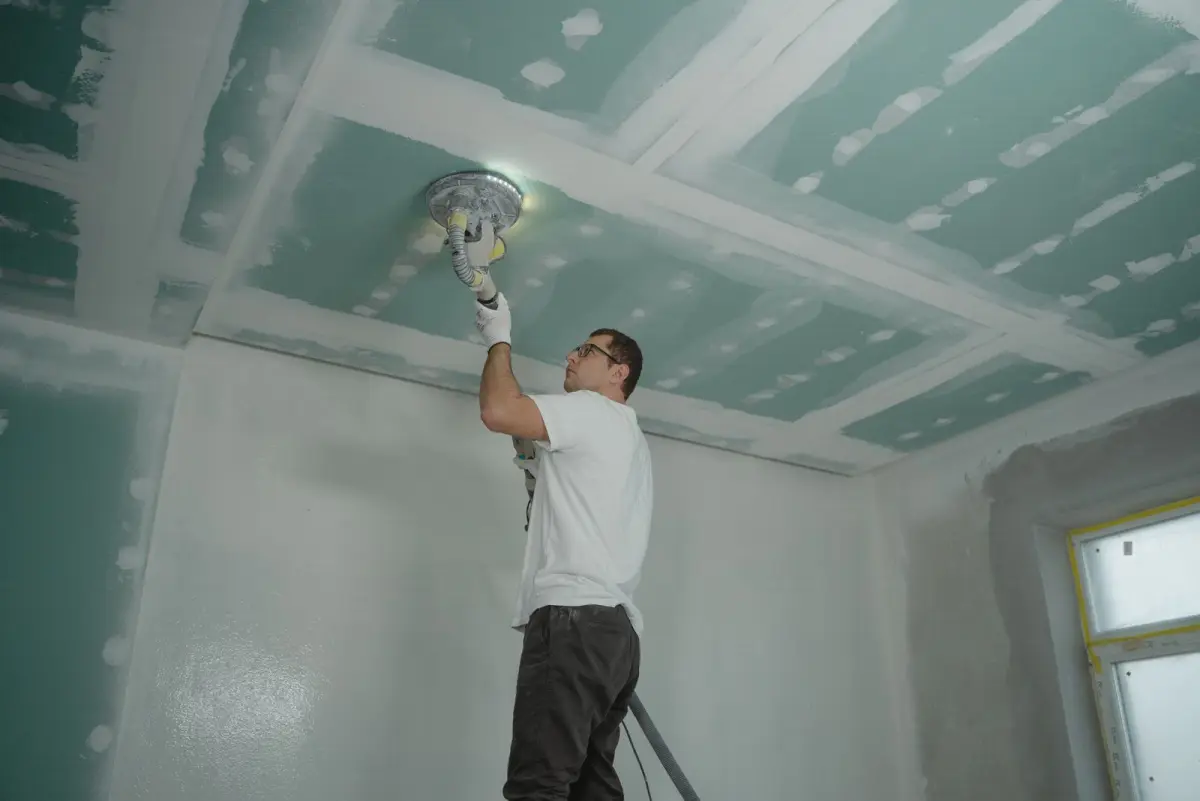 Professionnel lissant la surface d'un plafond